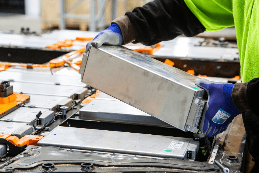 Gloved technician lifting a module from an opened electric vehicle battery pack