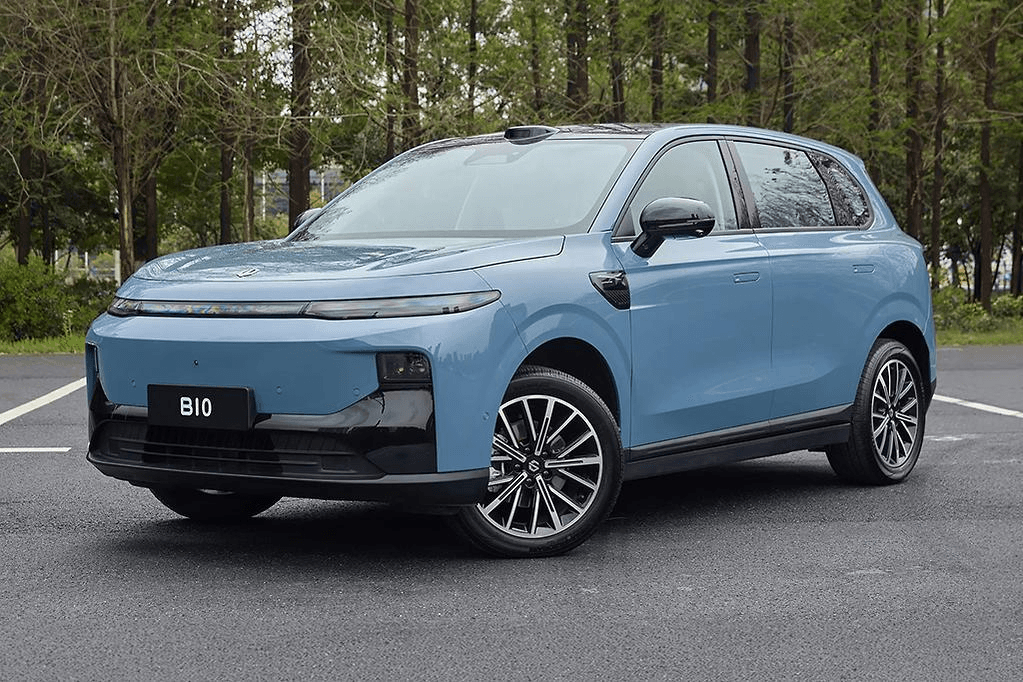 Blue electric vehicle parked beside a wooded area
